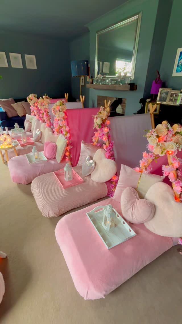 Pink sleepover party setup with floor mattresses, heart pillows, and floral teepees.