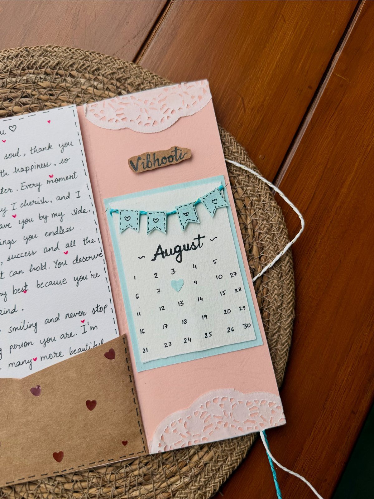 Pink handmade book cover with lace, a calendar, and a handwritten letter.