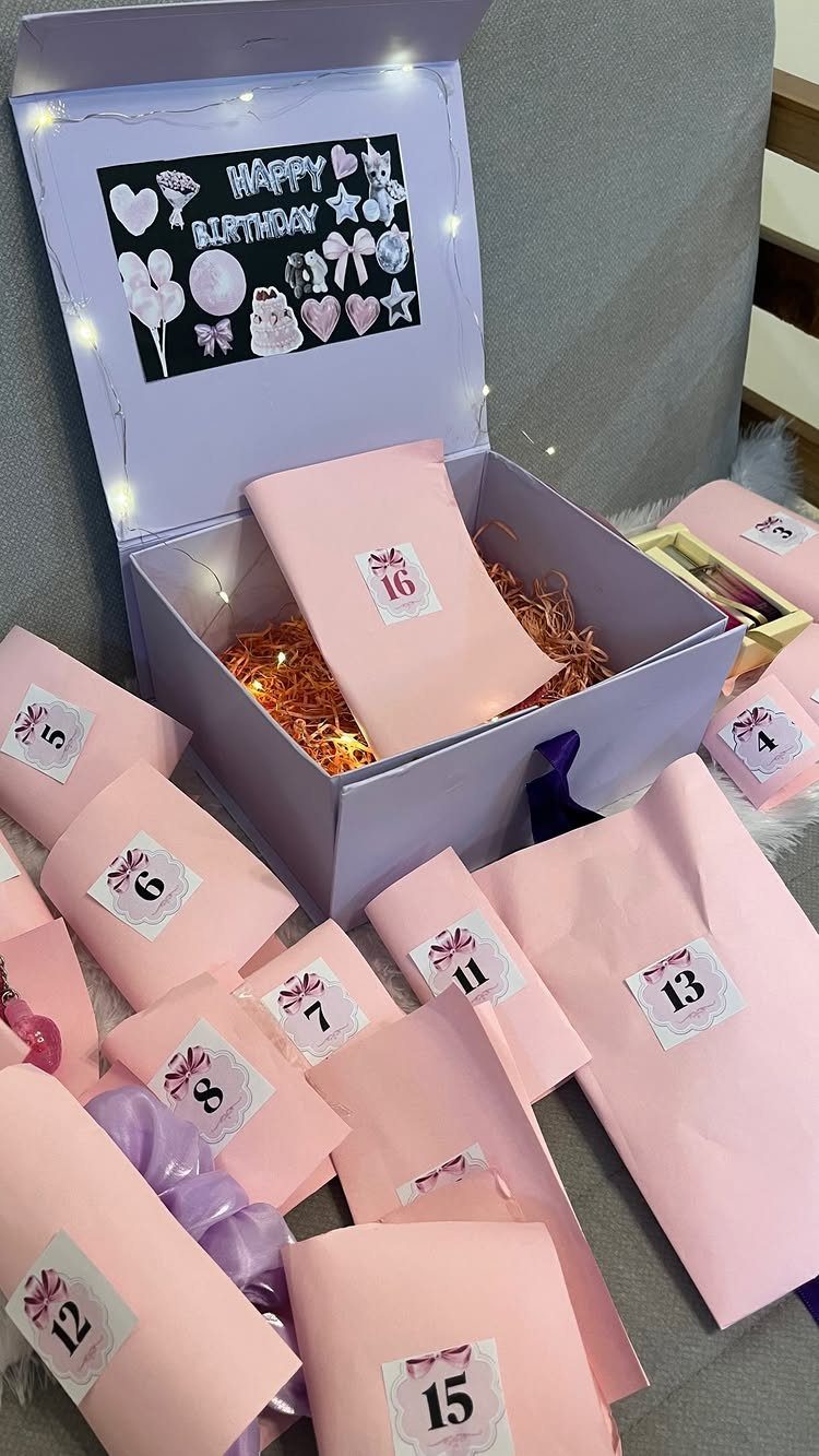 Purple birthday gift box with numbered pink envelopes and fairy lights.