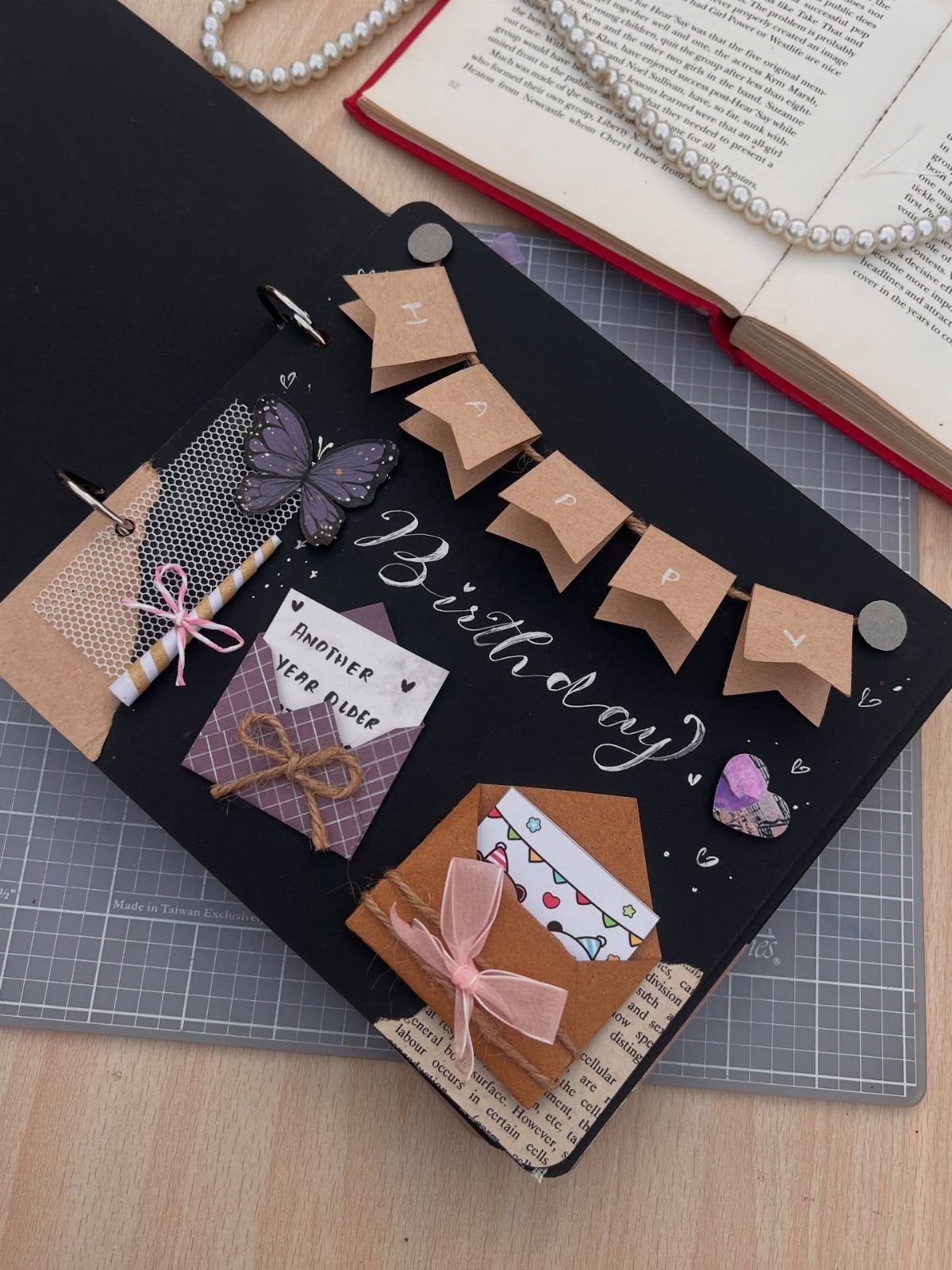 Birthday scrapbook page with small envelopes, a banner, and a purple butterfly decoration.