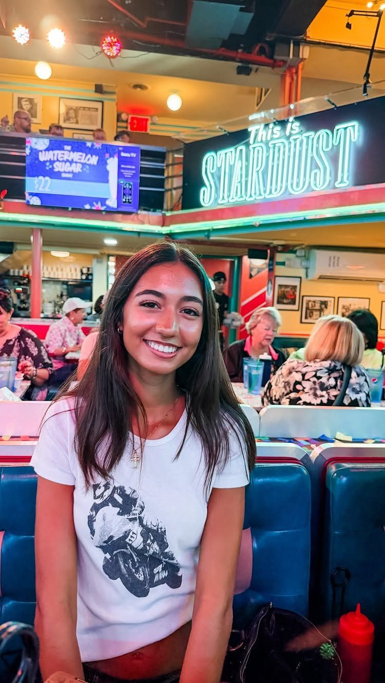 Teenage girl smiling while sitting in a blue booth at Stardust Diner