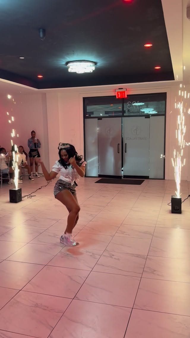 Young woman dancing between indoor sparkler fountains at a celebratory party event