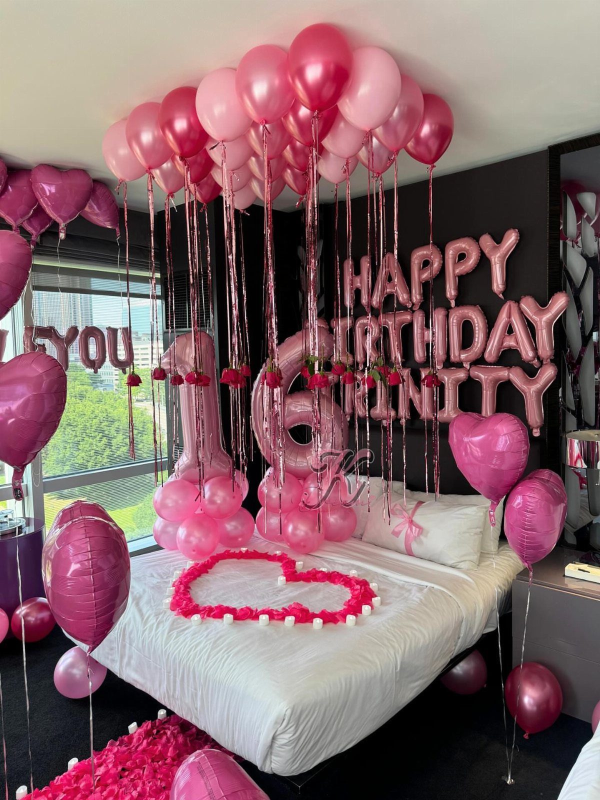 Hotel room decorated with pink balloons and silver birthday lettering for a 16th birthday.