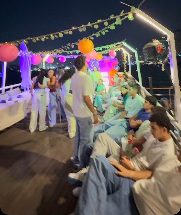 Teenagers celebrating on a decorated boat deck at night with colorful lanterns.