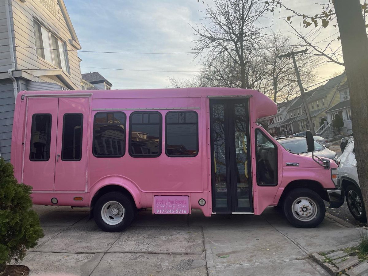 Bright pink party bus parked on a residential driveway under a clear sky.