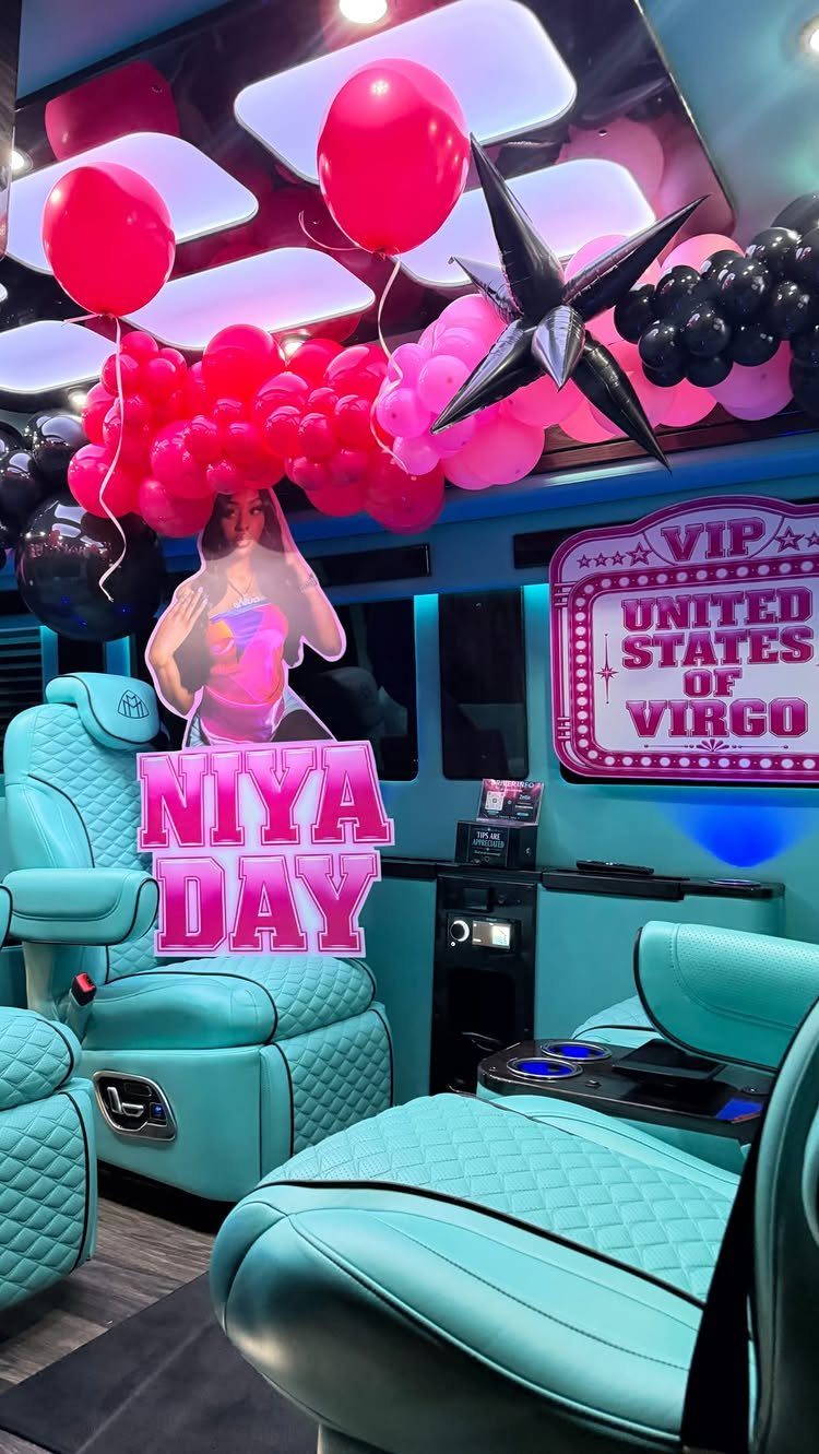 Turquoise party bus interior decorated with pink balloons and personalized neon signs.