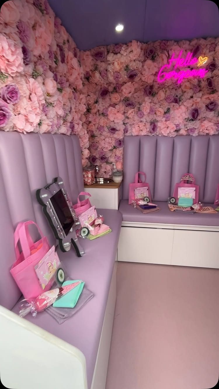 Purple party bus interior with pink flower wall and neon sign and gift bags