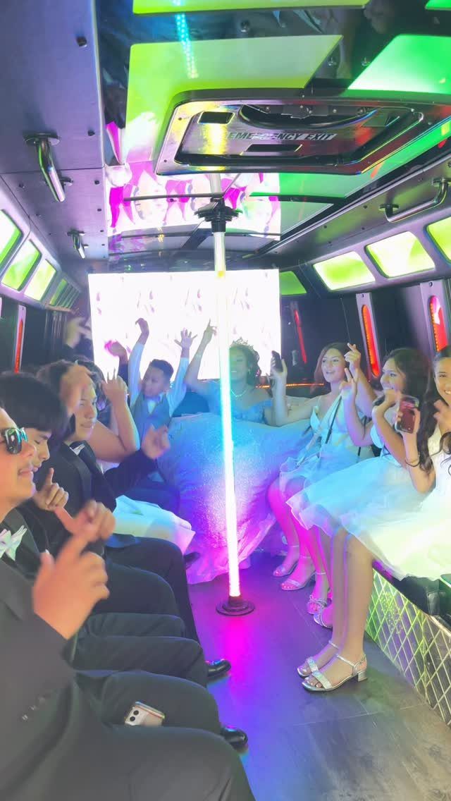 Teenagers in formal wear celebrating inside a party bus with neon lighting.