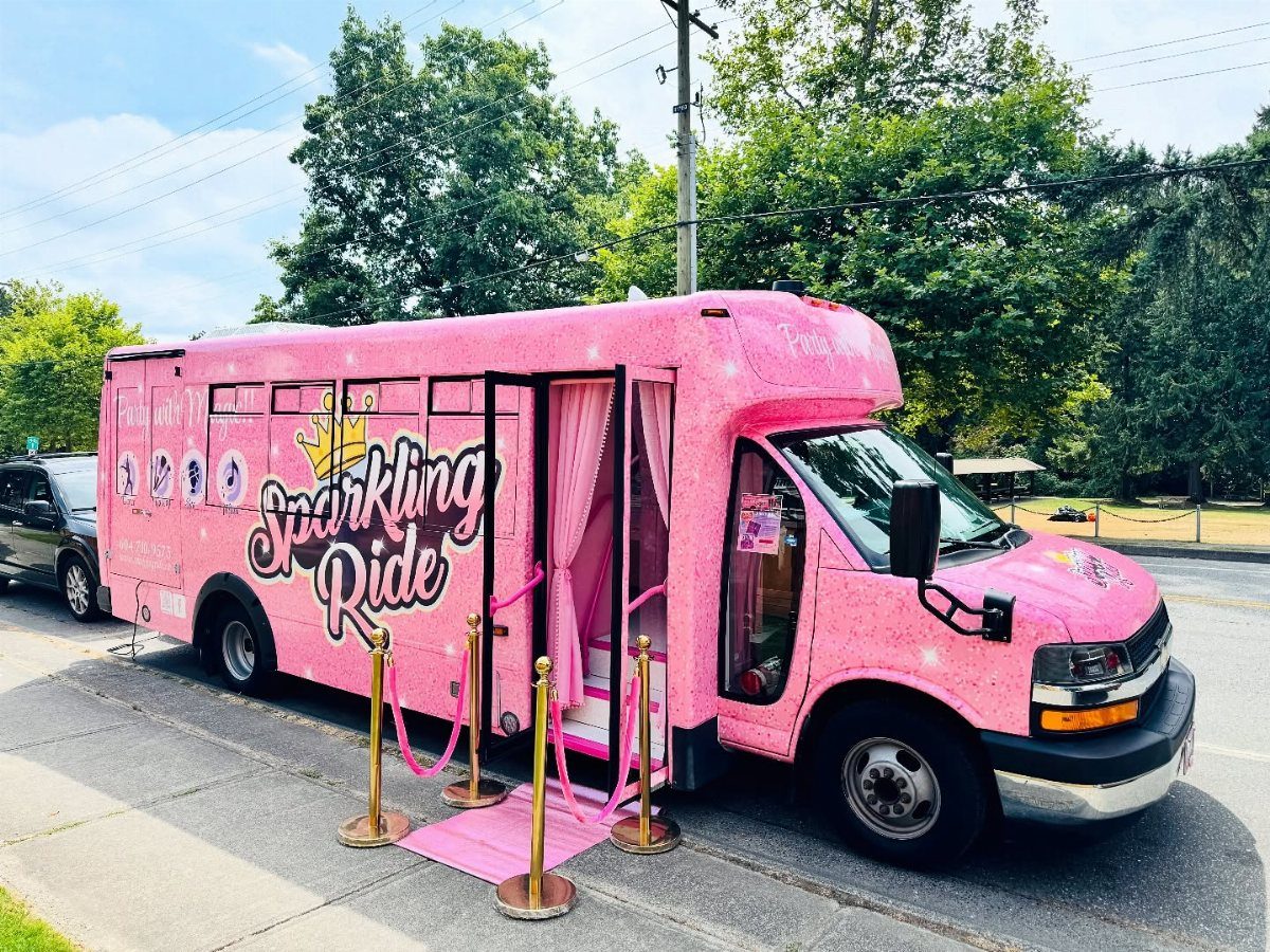 Pink glittery party bus with a pink carpet and gold stanchions entrance.