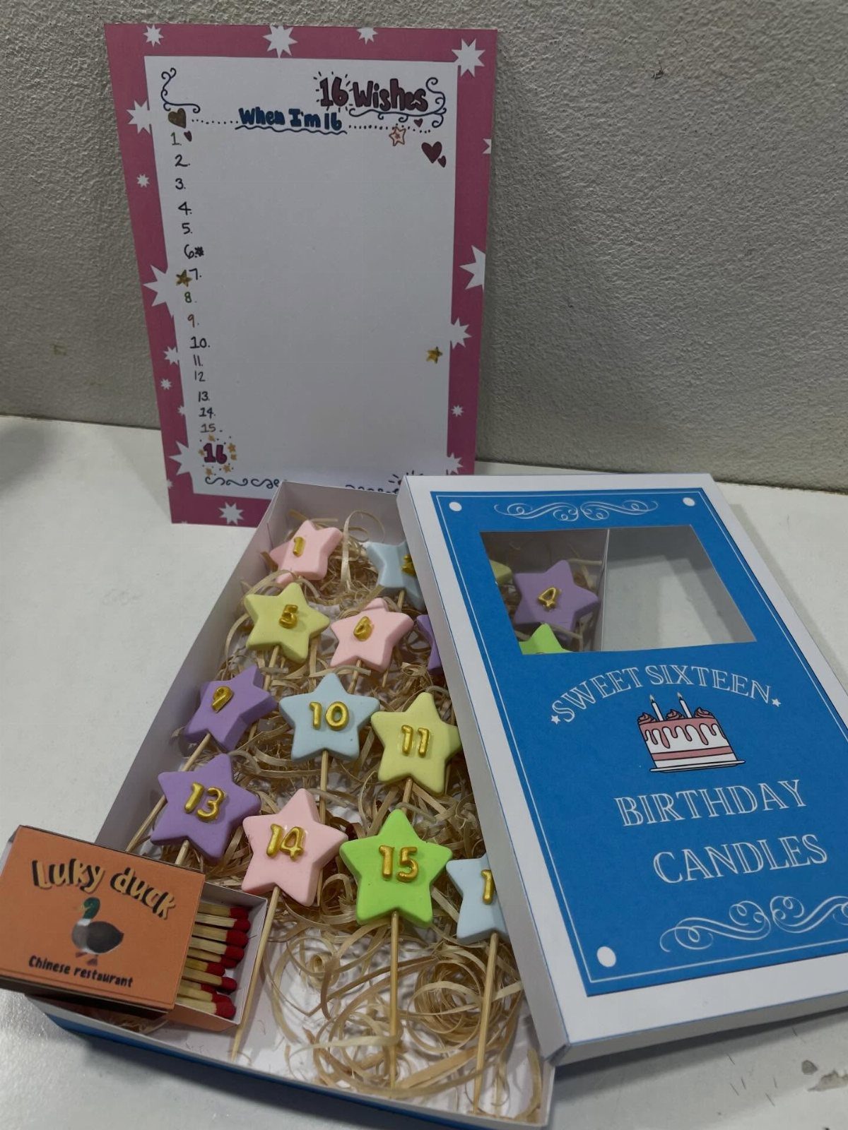Pastel star-shaped birthday candles numbered 1 to 16 in a blue gift box.