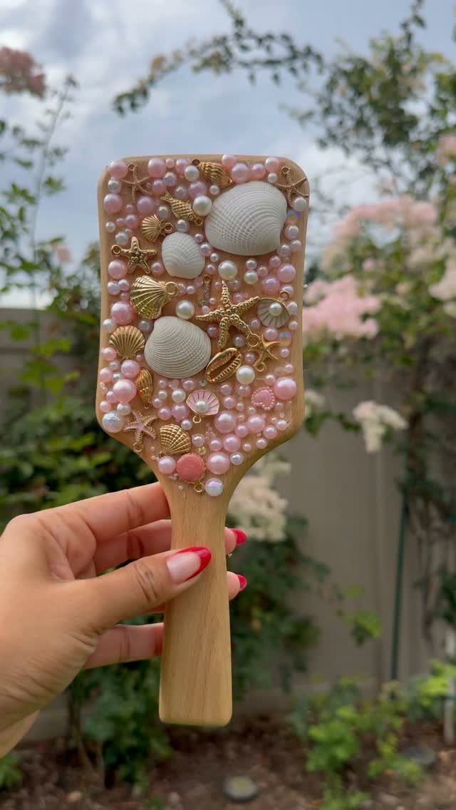 Decorated wooden hairbrush with pink pearls, seashells, and gold starfish charms.
