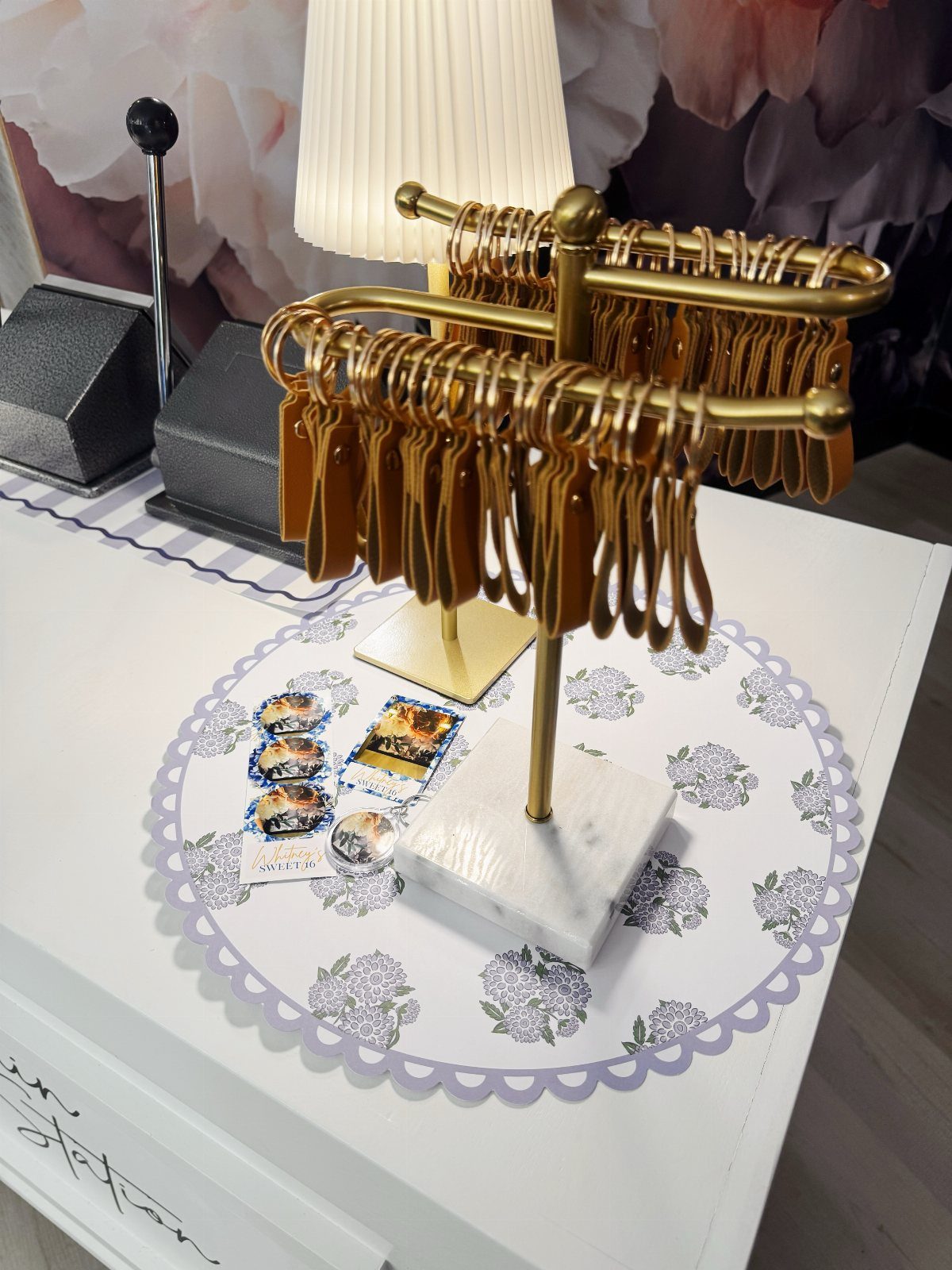 Gold racks holding brown leather keychains as party favors on a white table