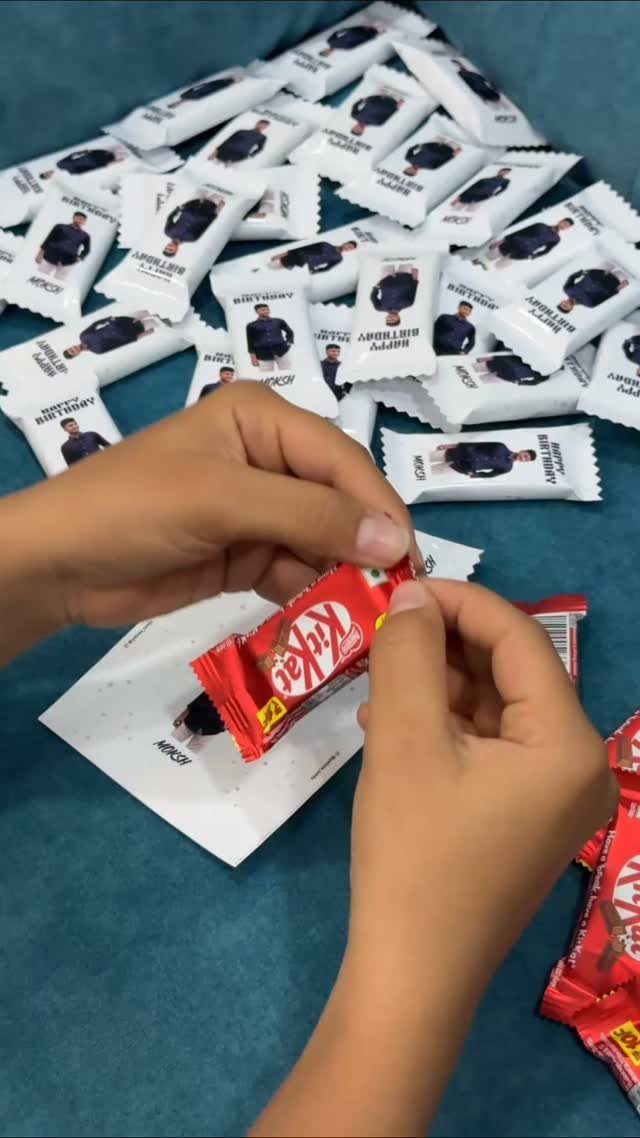 Hands opening a KitKat bar with a custom birthday photo wrapper among many others.