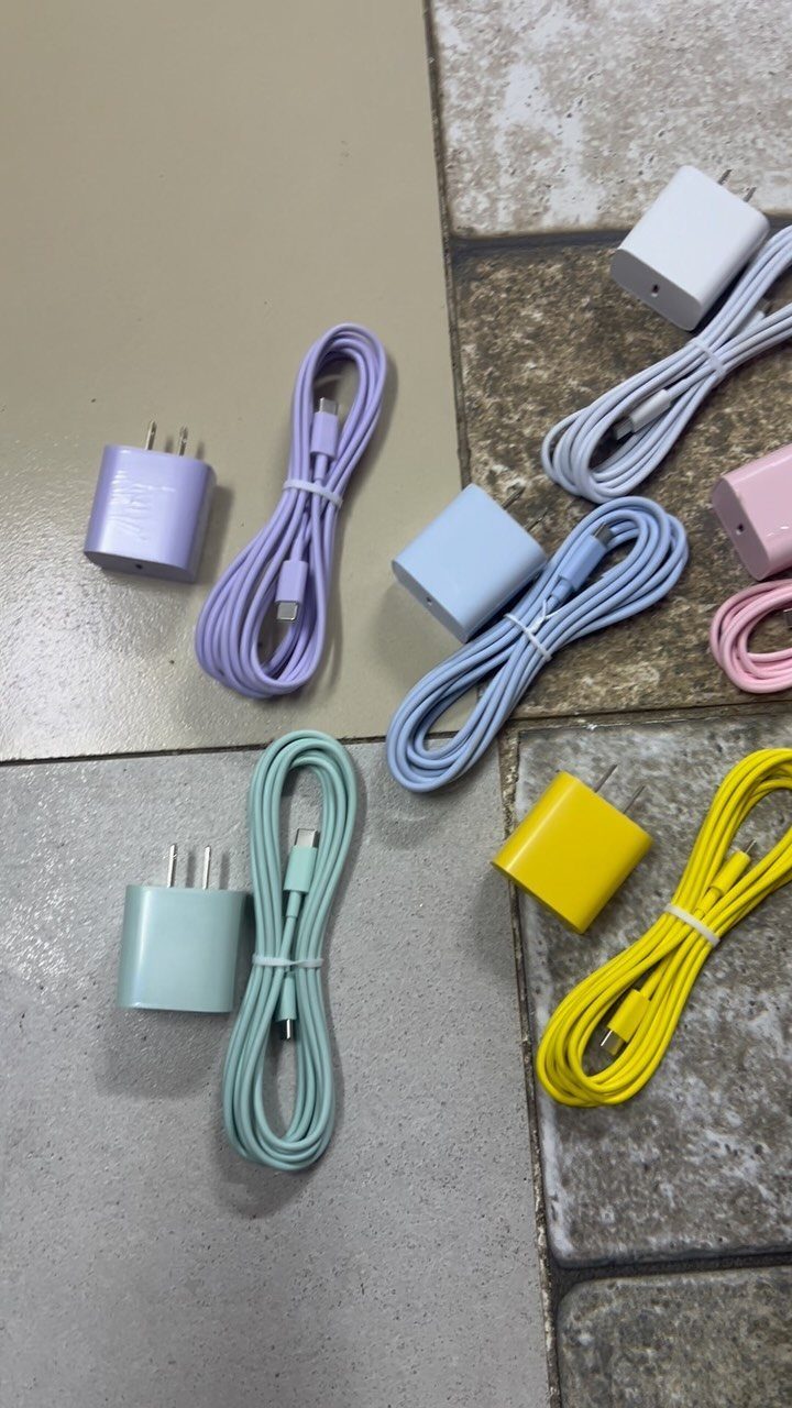 Pastel colored wall charger blocks and matching USB cables on a tiled floor.