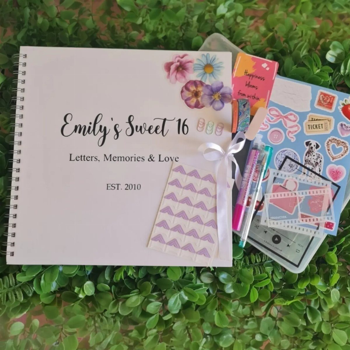 Personalized Sweet 16 notebook with floral cover and stationery on green leaves