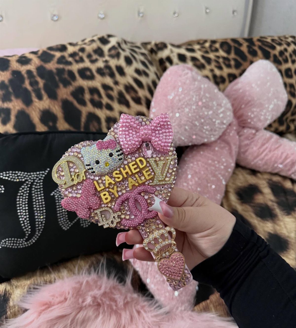 Rhinestone heart-shaped mirror with Hello Kitty and text held against plush pillows.