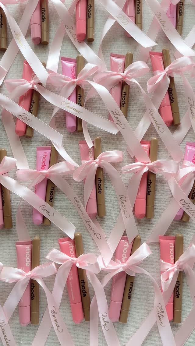 Rhode beauty products tied with pink ribbons and personalized names as party favors.