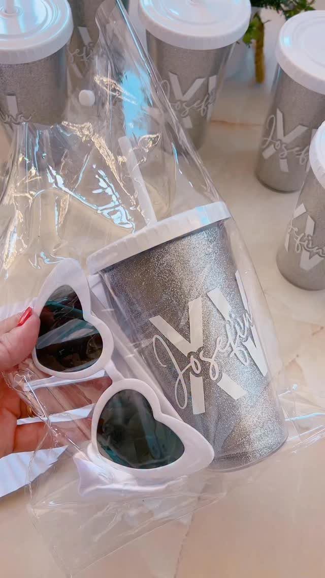 Silver glittery personalized tumbler and heart sunglasses in a clear plastic gift bag.