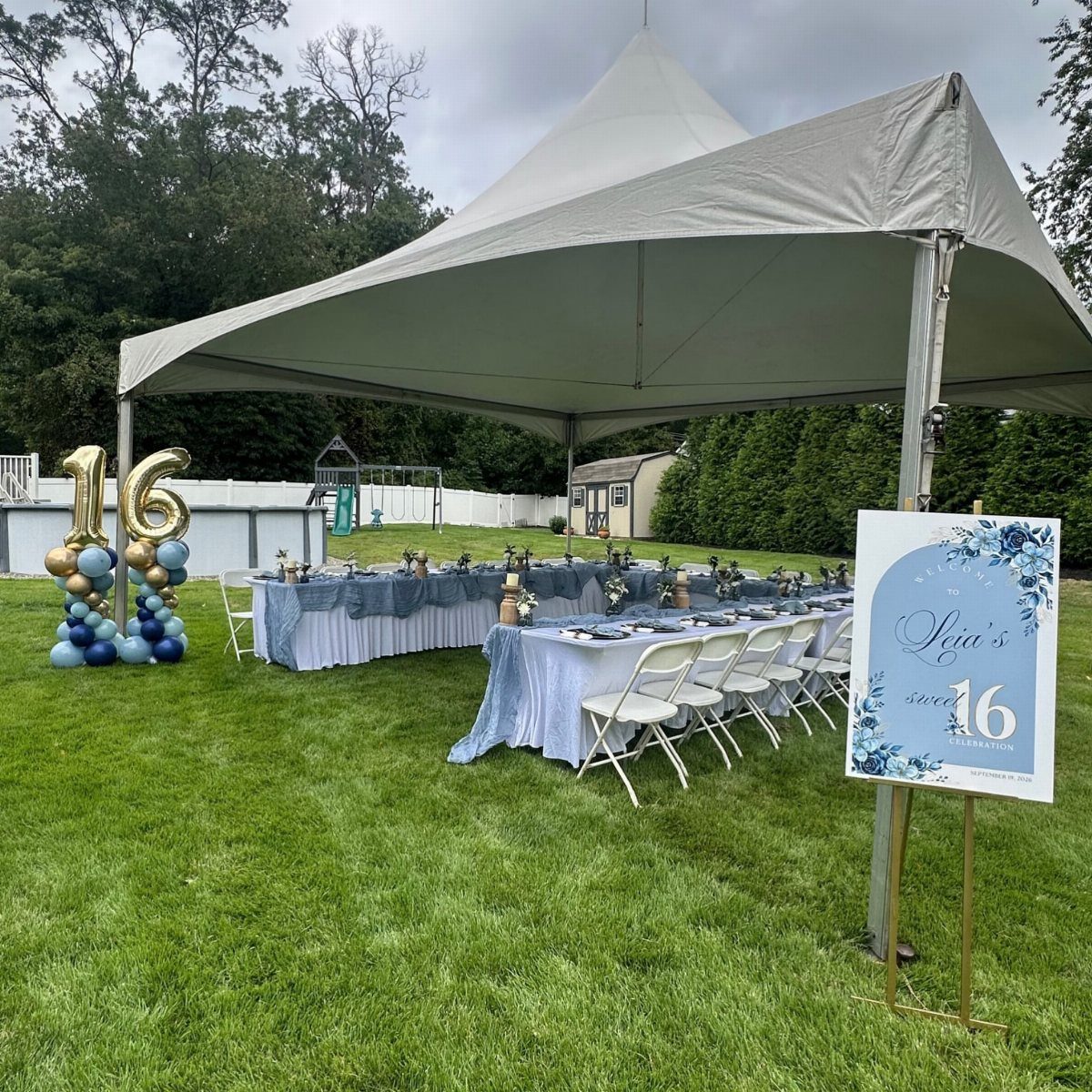 Outdoor sweet 16 party setup with white tent, blue tables, and gold balloons.