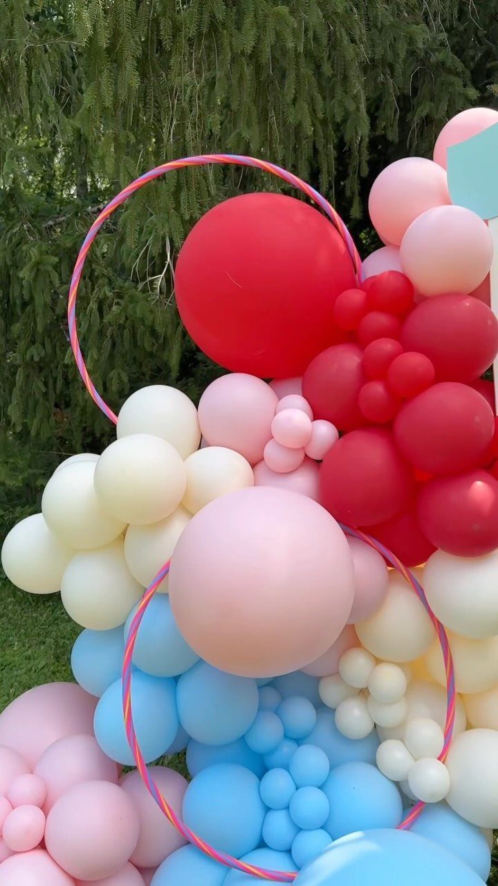 Colorful balloon arch with red, pink, and blue balloons and pink circular hoops.