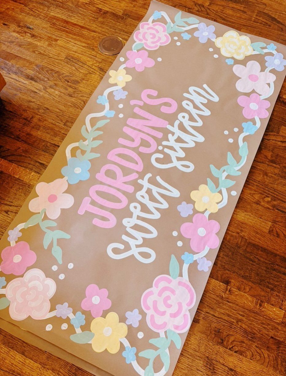 Hand-painted brown paper banner for a sweet sixteen party with colorful floral borders.