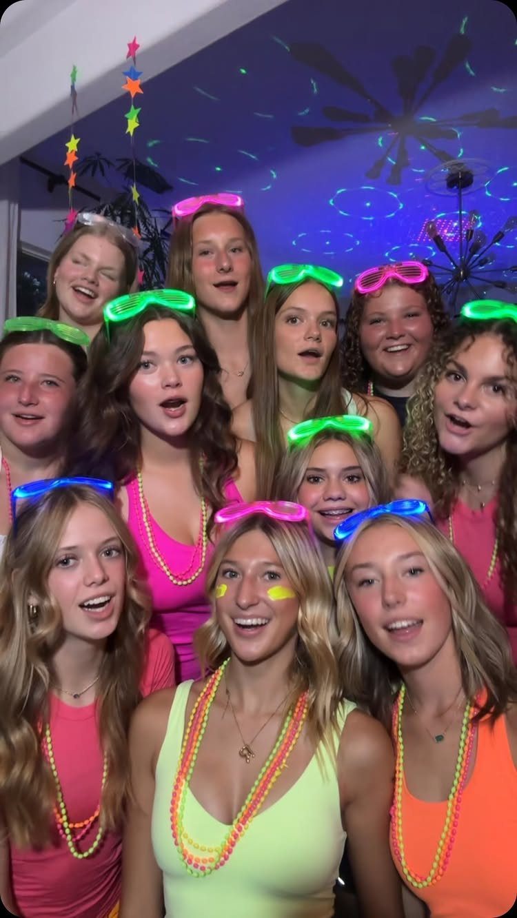 Teenage girls wearing neon clothes and glowing accessories at a party.