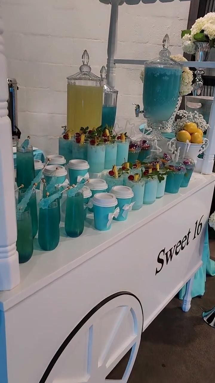 White beverage cart with blue and yellow drinks for a Sweet 16 party.