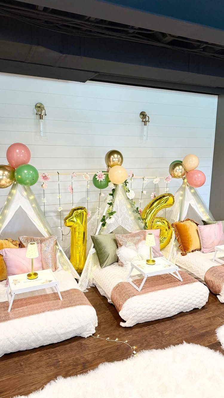Three white teepee tents with pink and gold bedding and number 16 balloons.