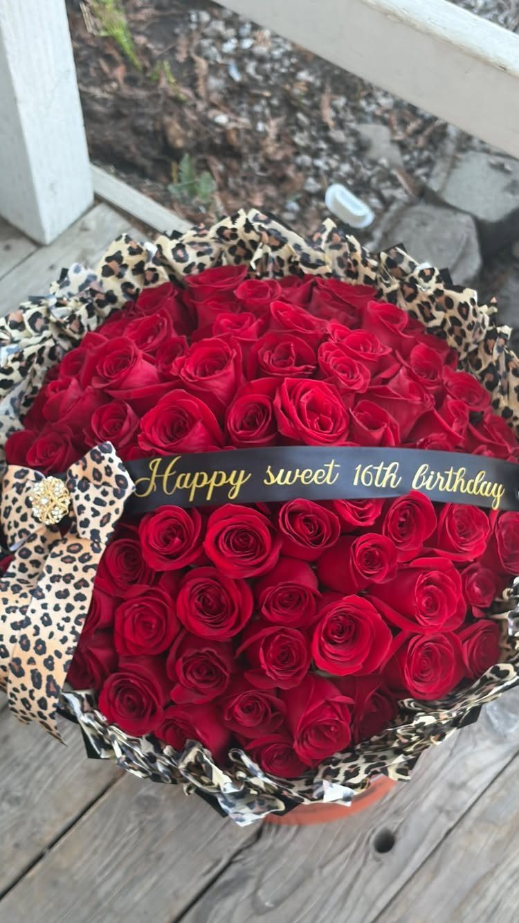 Large bouquet of red roses with leopard print wrap and sweet 16 ribbon.