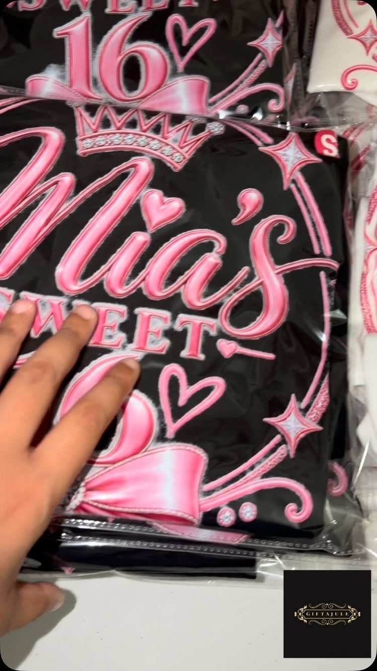 Black t-shirts with pink Mia's Sweet 16 graphics in plastic packaging