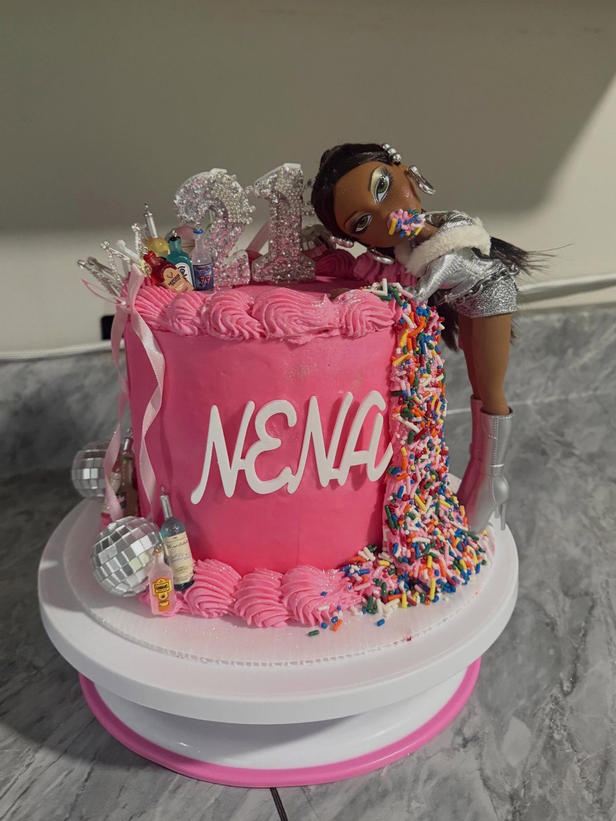Pink Barbie cake with colorful sprinkles, a silver 21 topper, and a doll.