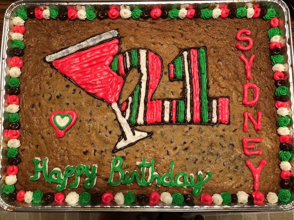Chocolate chip cookie cake decorated with a red martini glass and number 21.