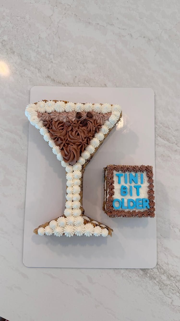 Martini glass shaped cookie cake with white and brown frosting and a small square cookie.