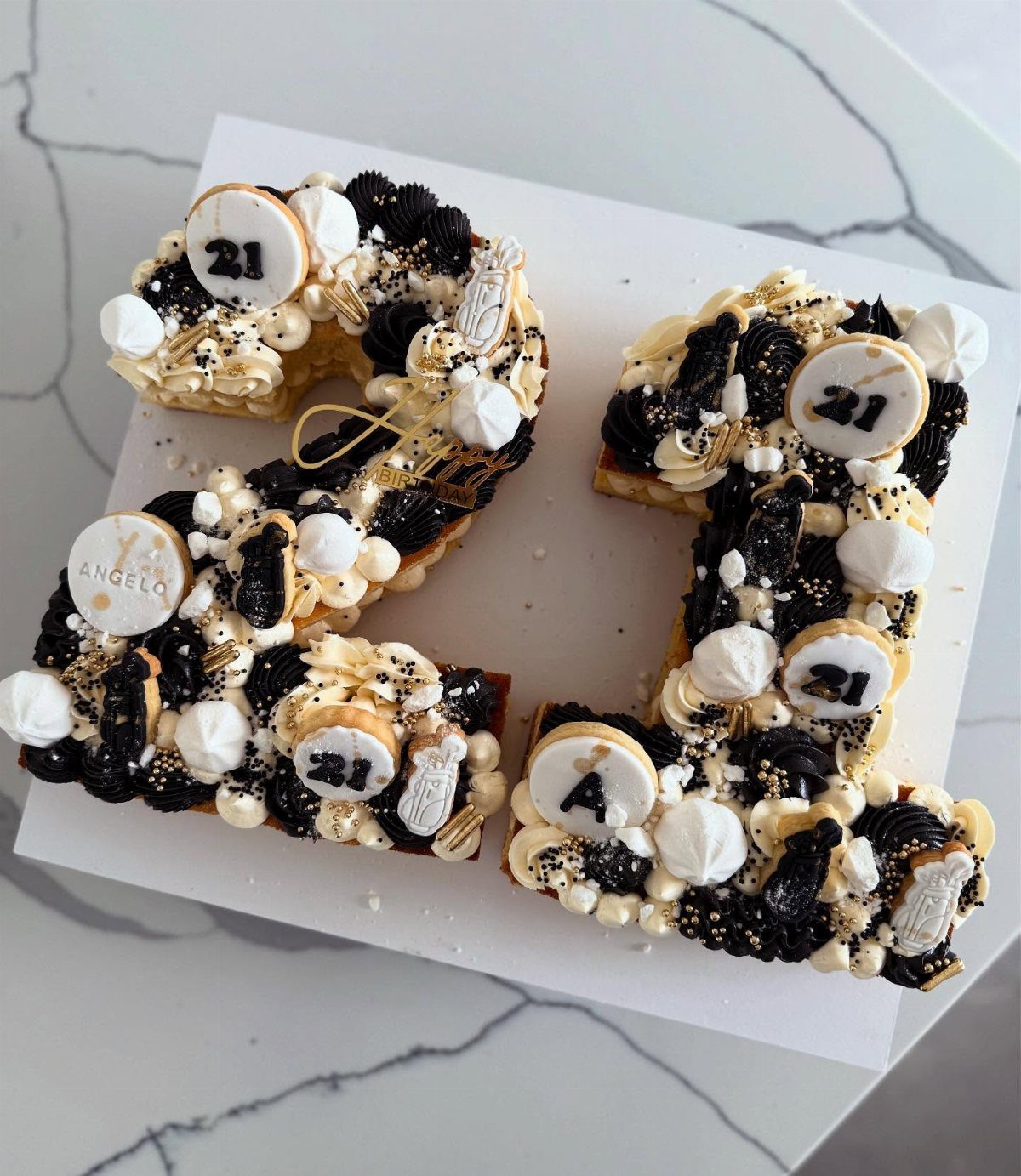 Number 21 cookie cake decorated with black and white frosting and gold sprinkles.