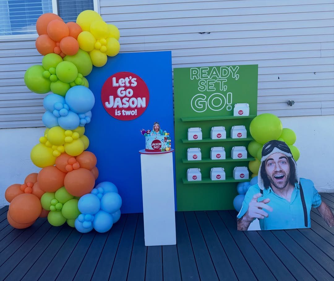 Birthday party setup with colorful balloons, themed backdrops, and a character cutout.