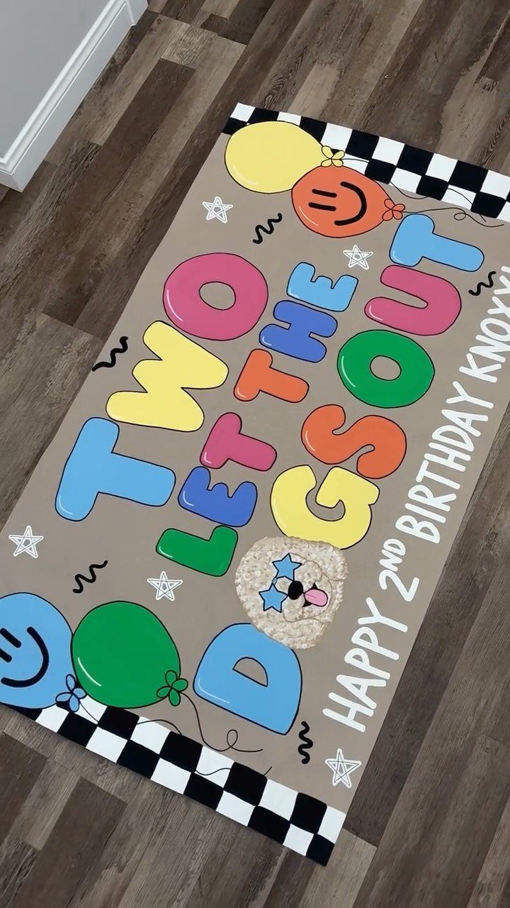 Party mat with colorful text reading Two Let the Dogs Out on wooden floor