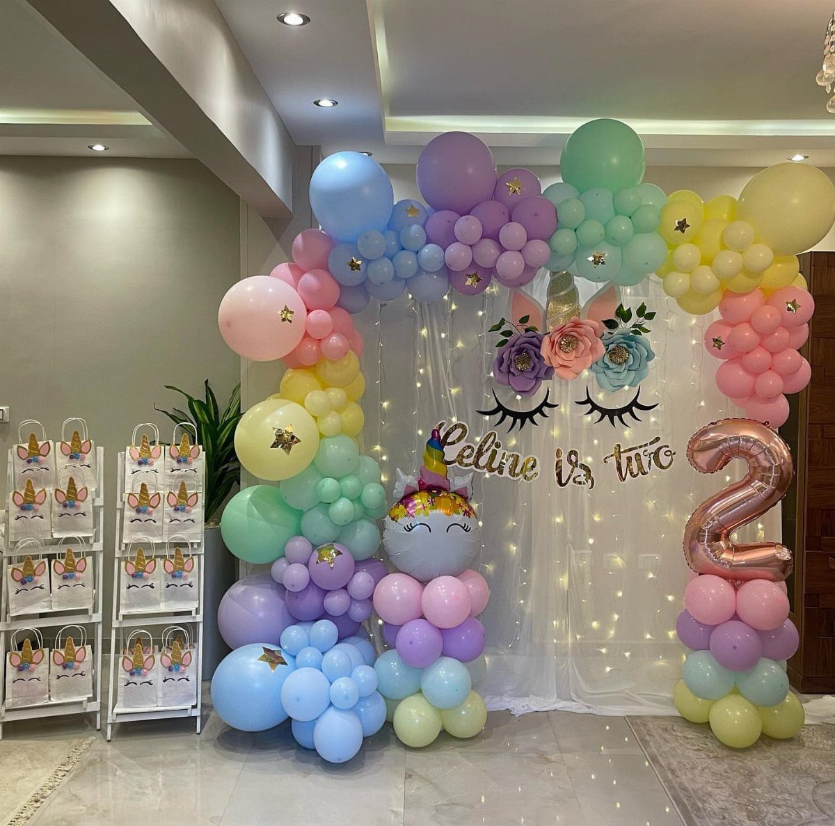 Pastel balloon arch and unicorn backdrop for a second birthday party celebration.