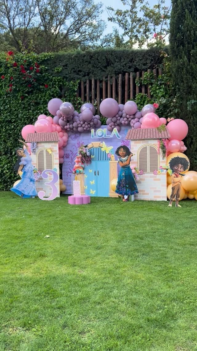 Encanto themed birthday party setup with colorful balloons, character cutouts, and number three.