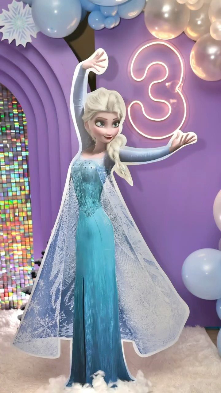Elsa cardboard cutout with a neon number 3 and blue balloons for a birthday.