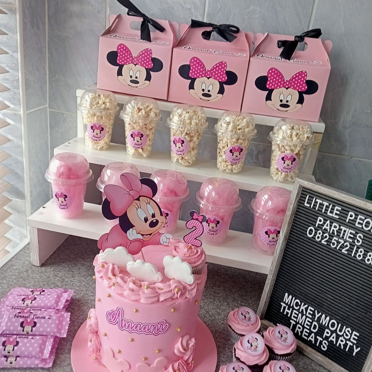 Minnie Mouse themed birthday treats including a pink cake, cupcakes, and gift boxes.