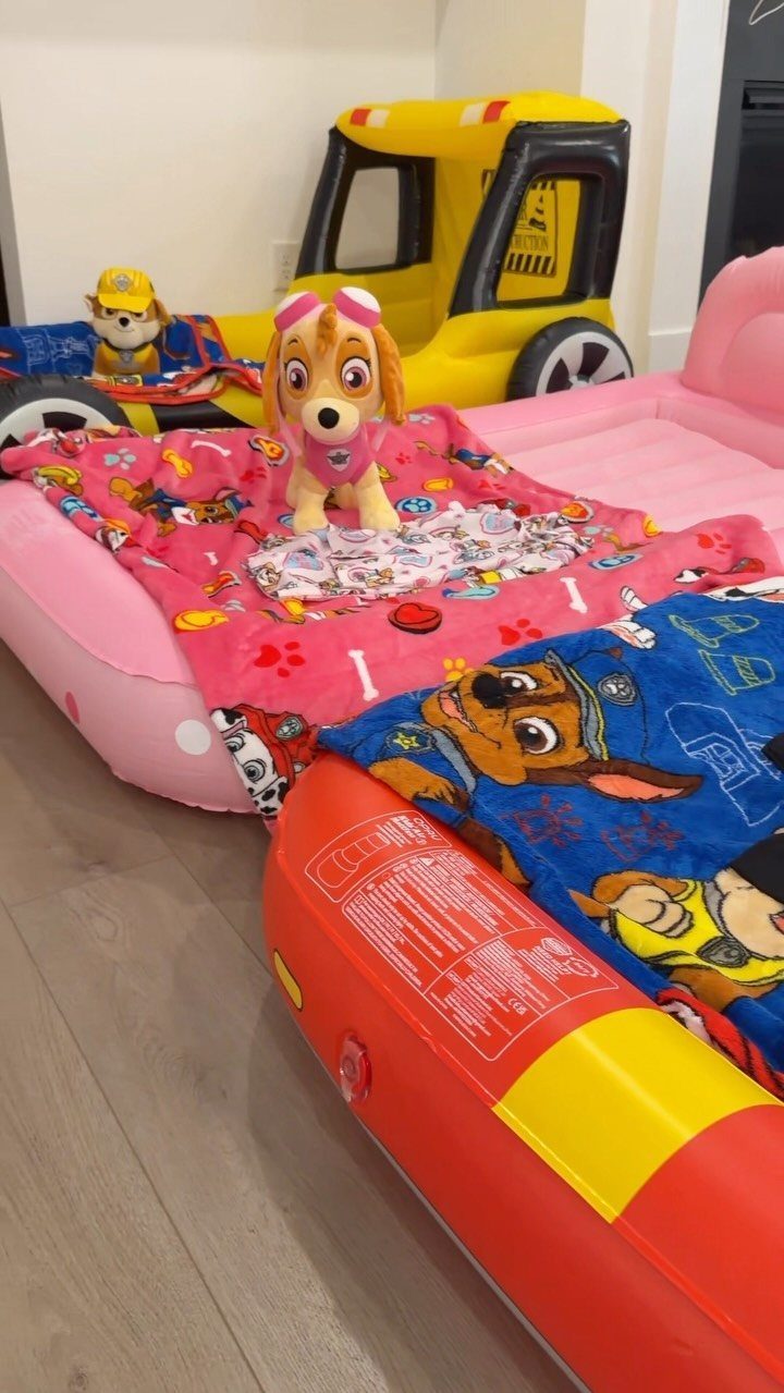 Pink inflatable lounge with Paw Patrol blankets and a plush pup toy.