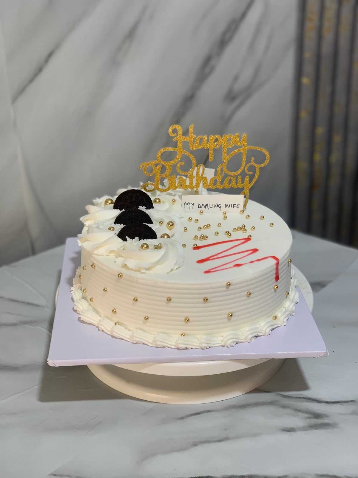Single tier white birthday cake with gold pearls and a gold Happy Birthday topper.