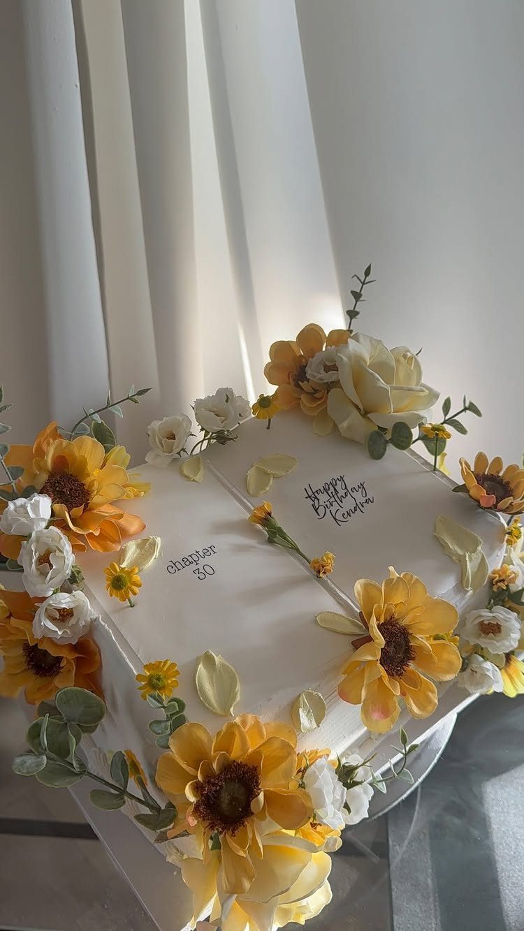 White square birthday cake decorated with yellow sunflowers and white floral accents.