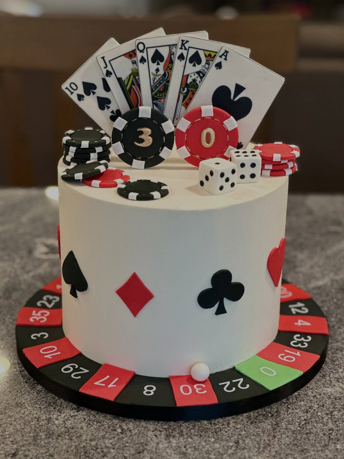 Gambling themed birthday cake with playing cards, poker chips, and a roulette base.