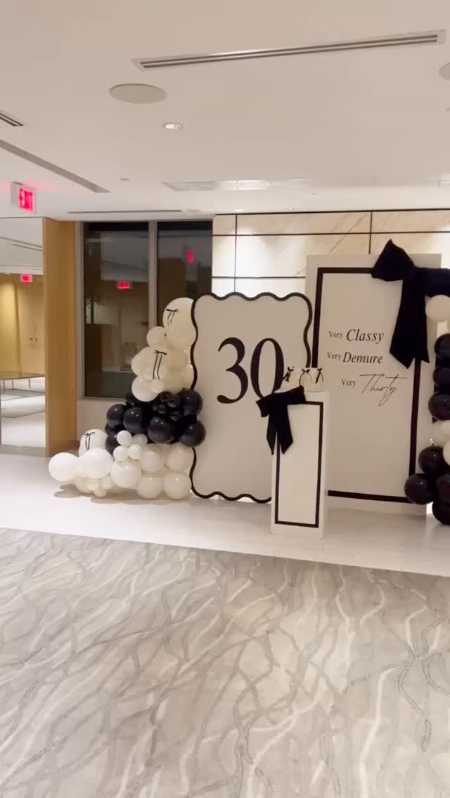 Black and white balloon arch and signs for a 30th birthday party celebration.