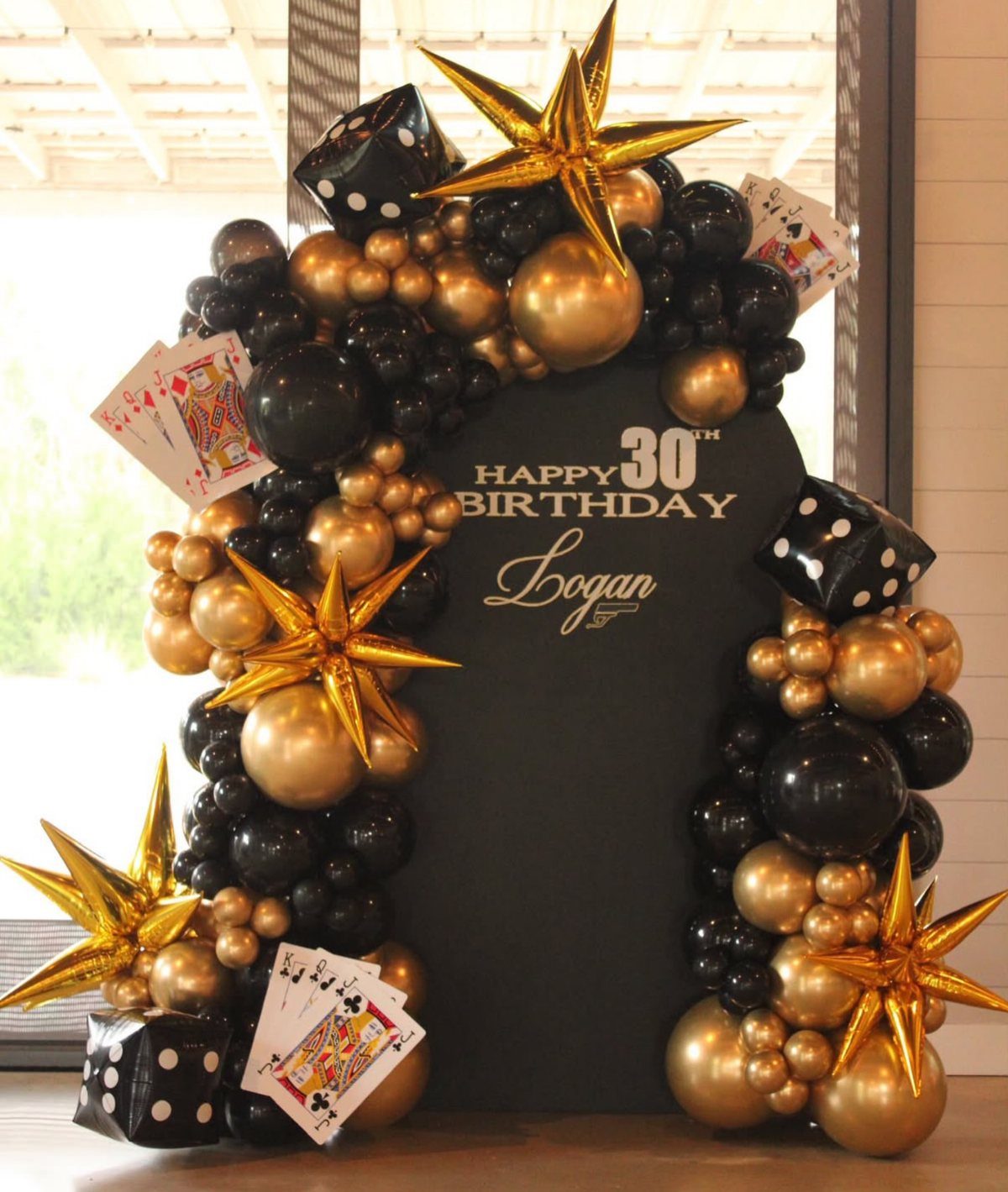 Black and gold balloon arch with dice and cards for a 30th birthday.