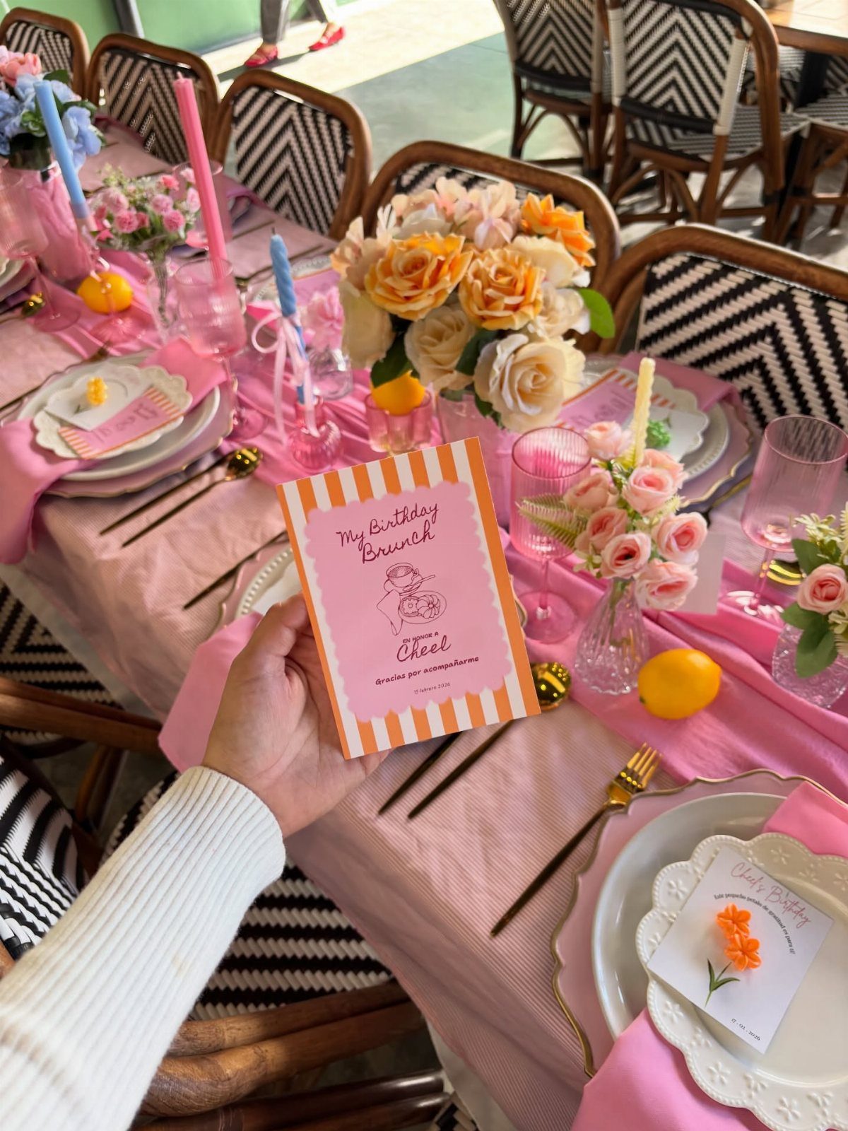 Birthday brunch invitation held over a sophisticated table with pink linens and roses.