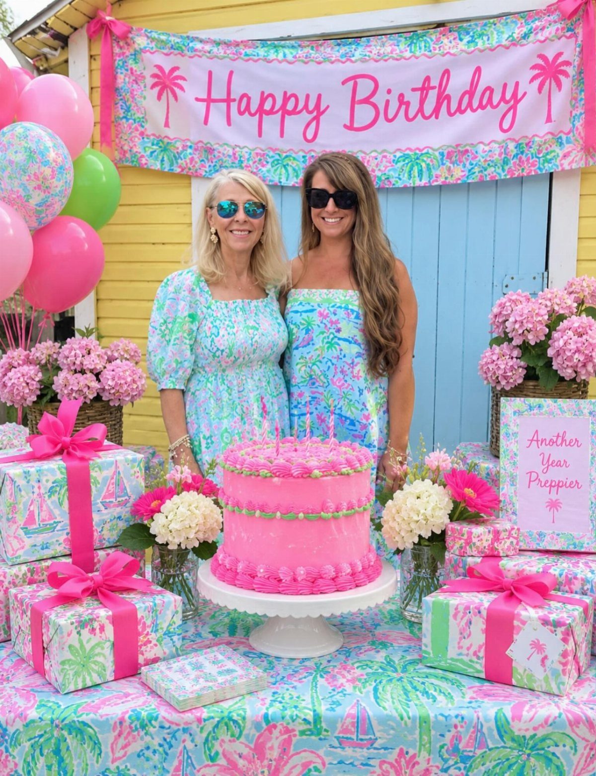 Two women in floral dresses celebrating a birthday with a pink cake and gifts.