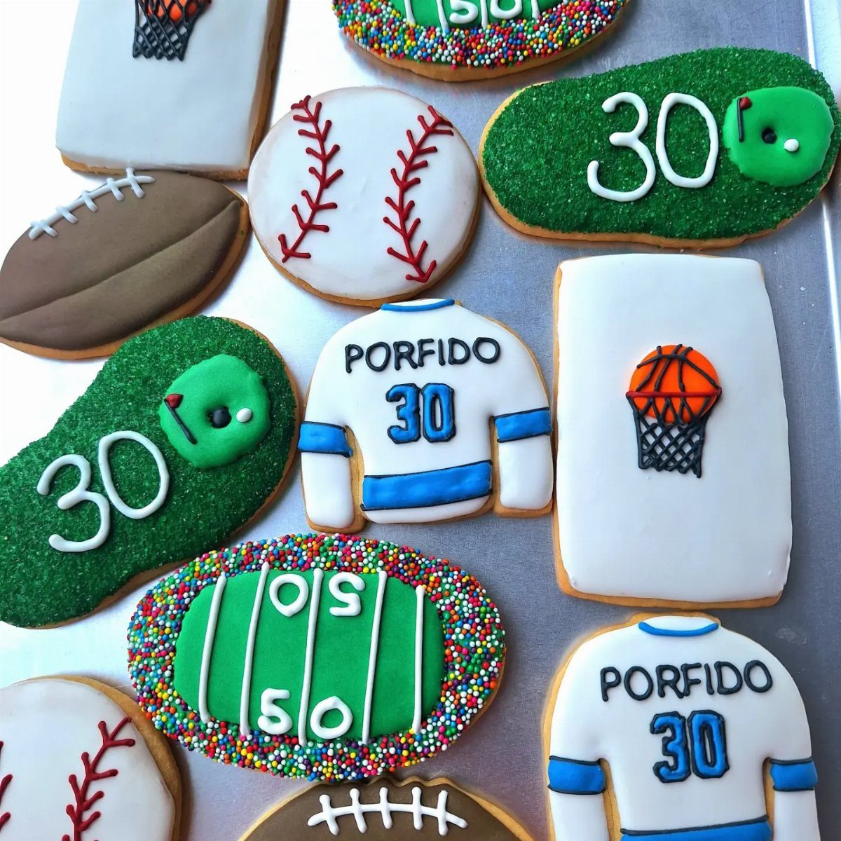 Sports-themed sugar cookies featuring footballs, baseballs, basketballs, and jerseys with the number 30.