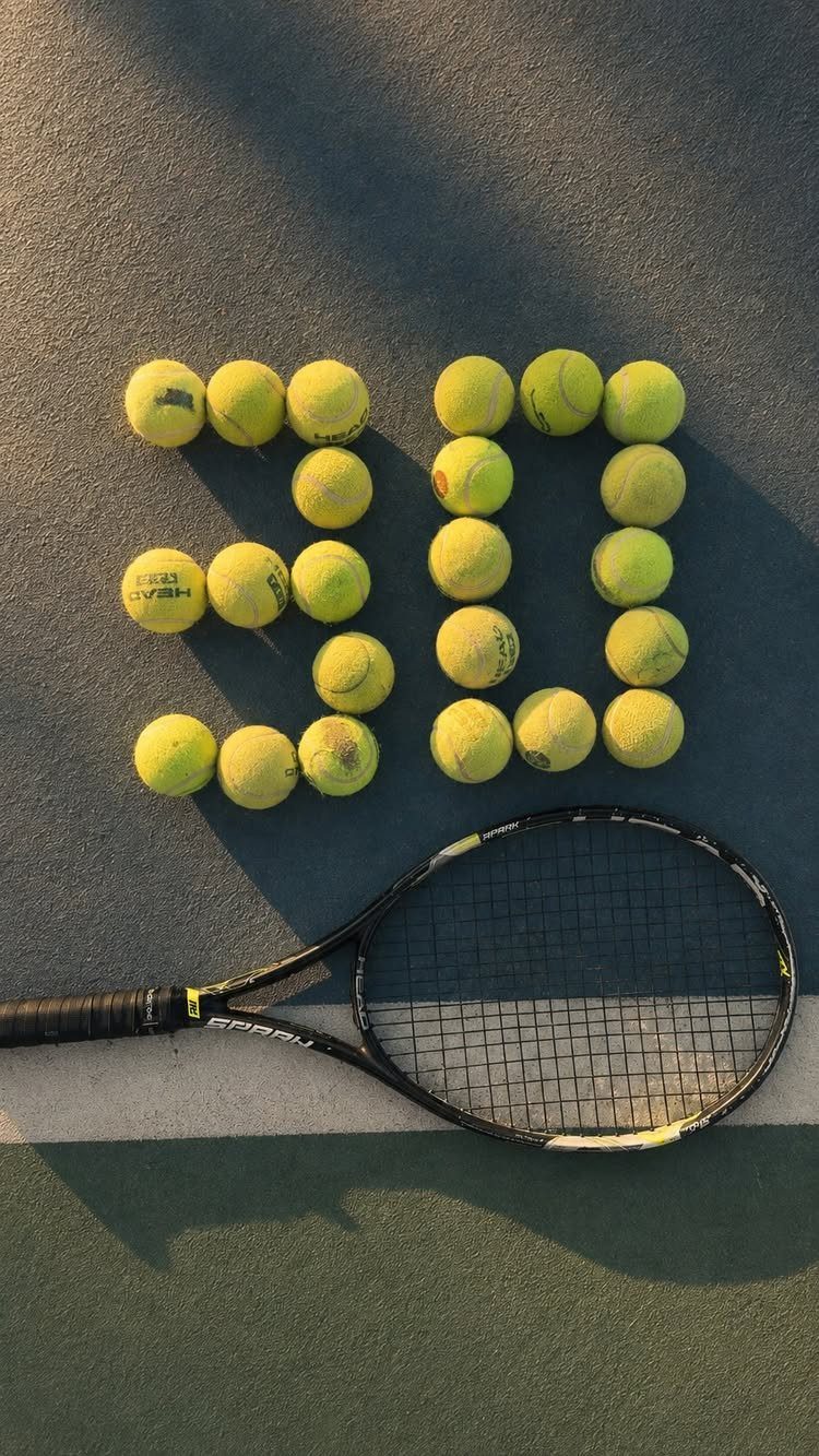 Tennis balls forming the number 30 on a court with a tennis racket.